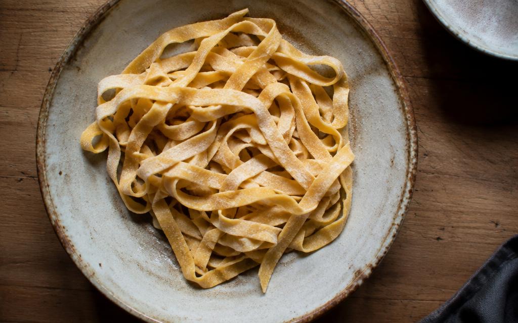 Fresh hand-cut tagliatelle on a rustic ceramic plate